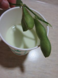 収穫した枝豆と枝豆のピューレを牛乳で溶いた飲み物がコップに入っている様子