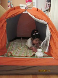 オレンジのテントの中に女児の利用者さんが寝そべっている様子