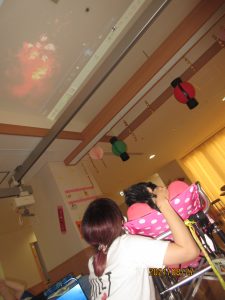 天井に赤く映し出されている花火の影像をスタッフと利用者さんが上を眺めている様子