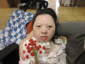 別の女性の利用者さんがたくさんの赤い千日紅の花のブーケを持っている様子