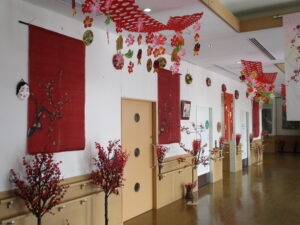 交流ホール壁際飾りの梅の花と節分の天井飾りの写真