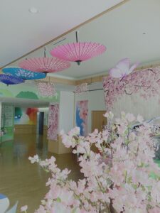 桜と天井から吊り下げた色とりどりの番傘の写真
