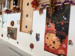 交流ホール壁に飾ったハロウィンのタペストリーと紅葉を模したモミジなどの飾りの写真