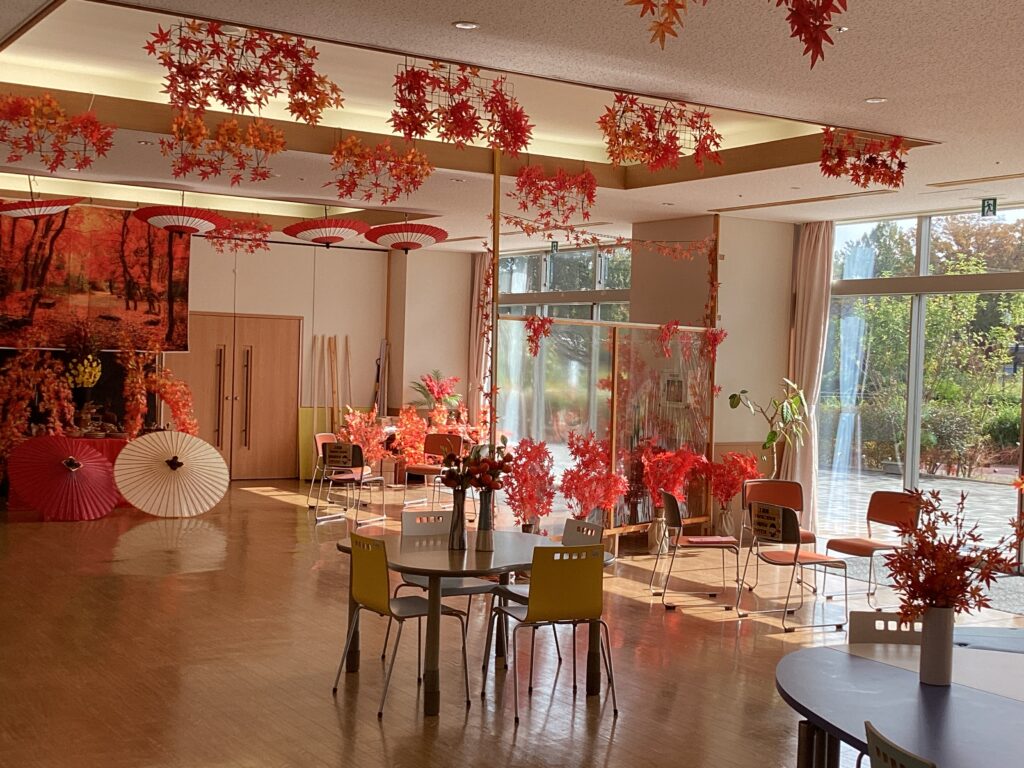 ホール全体に飾られた紅葉の赤い空間に午後の光が差し込んだ写真