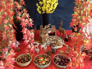 ホール正面のメイン飾り台の鹿や木の実、紅葉にイチョウを飾った写真
