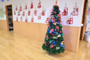フロア内の壁にたくさん飾り付けられた靴下の飾りと皆さんで飾ったクリスマスツリーの写真