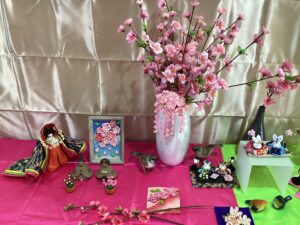 事務室脇のスペースに飾られた小さめの雛祭りグッズやうぐいすなどの小鳥や桃の造花の写真