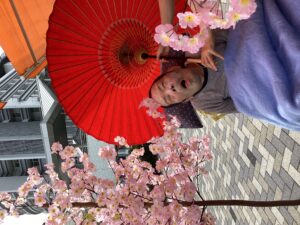桜の立ち木飾りや和傘と一緒に外で記念撮影する利用者さんの写真３