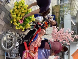 桜の立ち木飾りや和傘と一緒に外で記念撮影する利用者さんの写真１