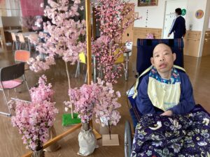 桜の立ち木飾りや和傘と一緒に外で記念撮影する利用者さんの写真１０