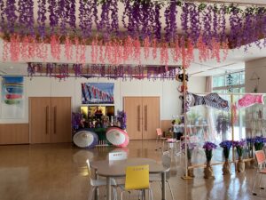 ホールの天井からピンクと紫の藤の花が枝垂れるように飾った写真