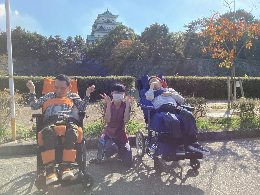 公園で名古屋城をバックに利用者さん２人とスタッフが写った写真２