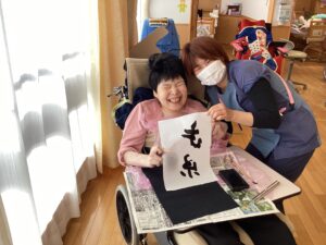 利用者さんが作品を持ってスタッフと一緒に笑顔を見せている写真