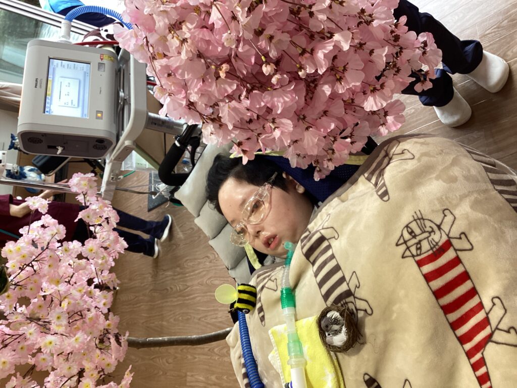 交流ホール内の桜の飾りと一緒に写したした利用者さんの写真