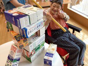 上手に牛乳パックが抜けて喜びの表情の利用者さんの写真
