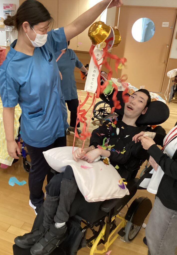 お誕生日のくす玉と利用者さんの写真