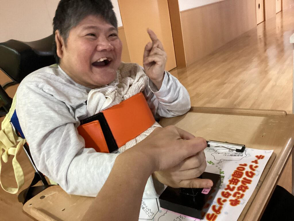 スタッフと一緒にスタンプを押す笑顔の利用者さん２の写真
